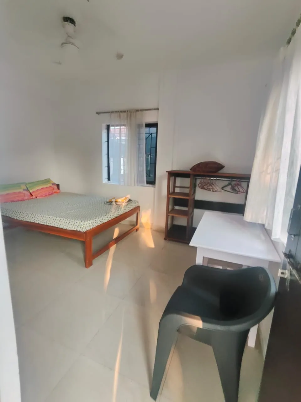 Student room at Alpesh Yoga with a double bed, open wardrobe shelves and a study desk