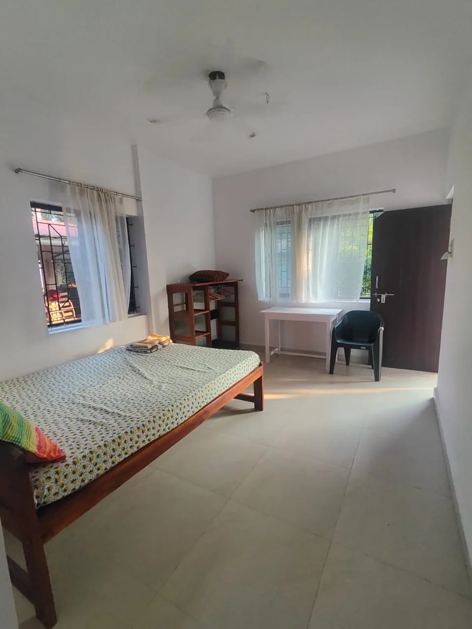 Bright student room at Alpesh Yoga with a double bed, study desk and two curtained windows