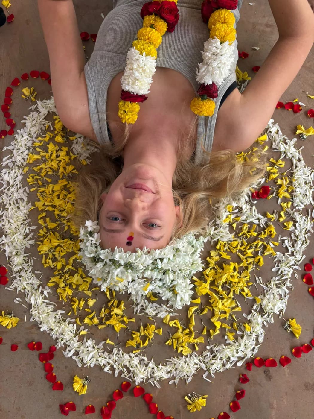 Overhead view of a graduating yoga student resting inside a marigold and jasmine flower mandala