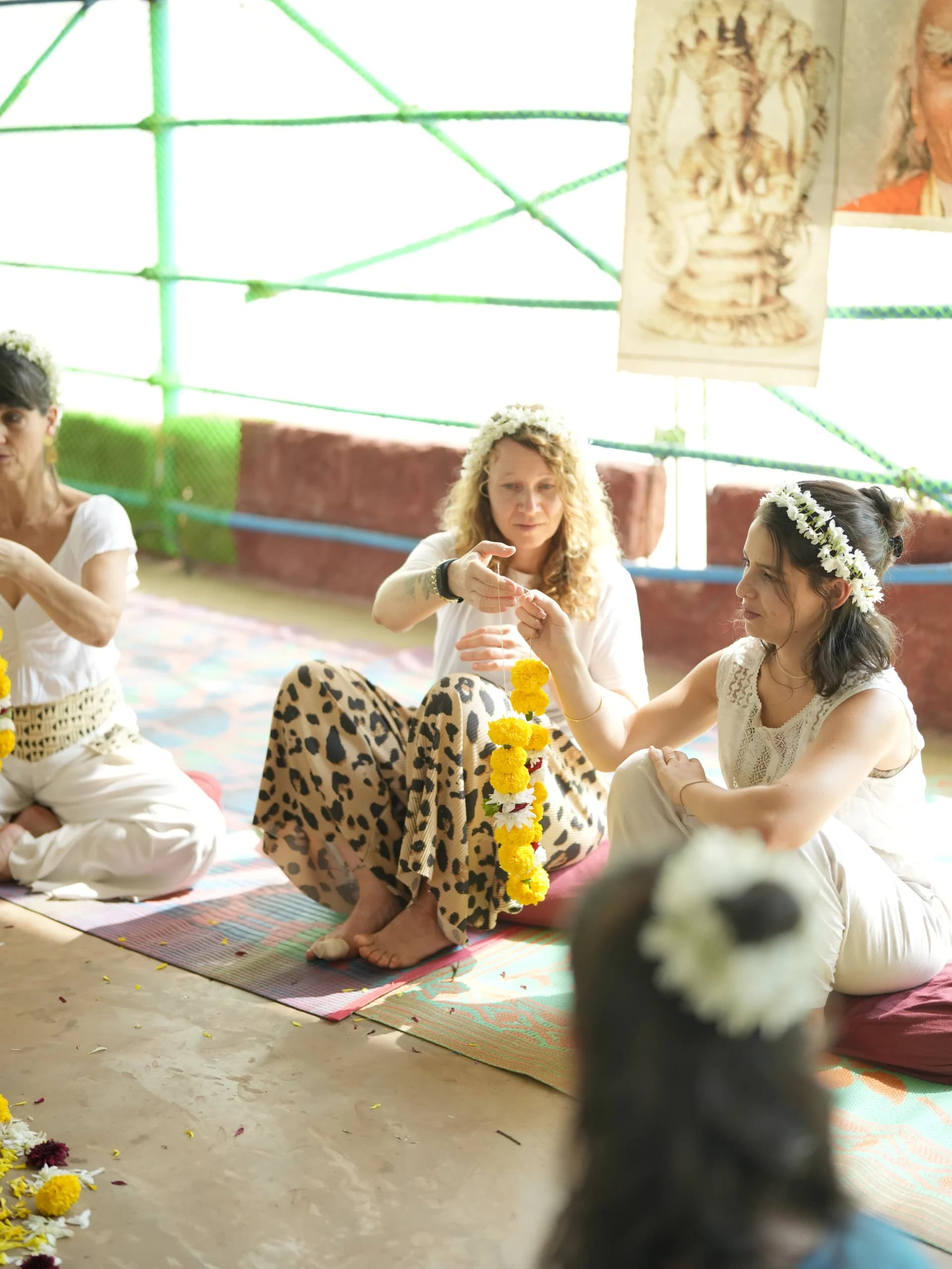 Yoga teacher training students threading marigold garlands during a traditional ceremony at the shala