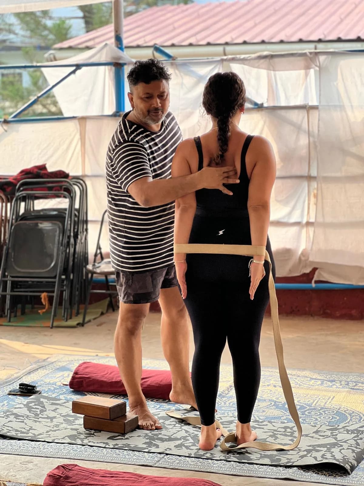 Teacher giving a hands-on alignment adjustment during a yoga teacher training class