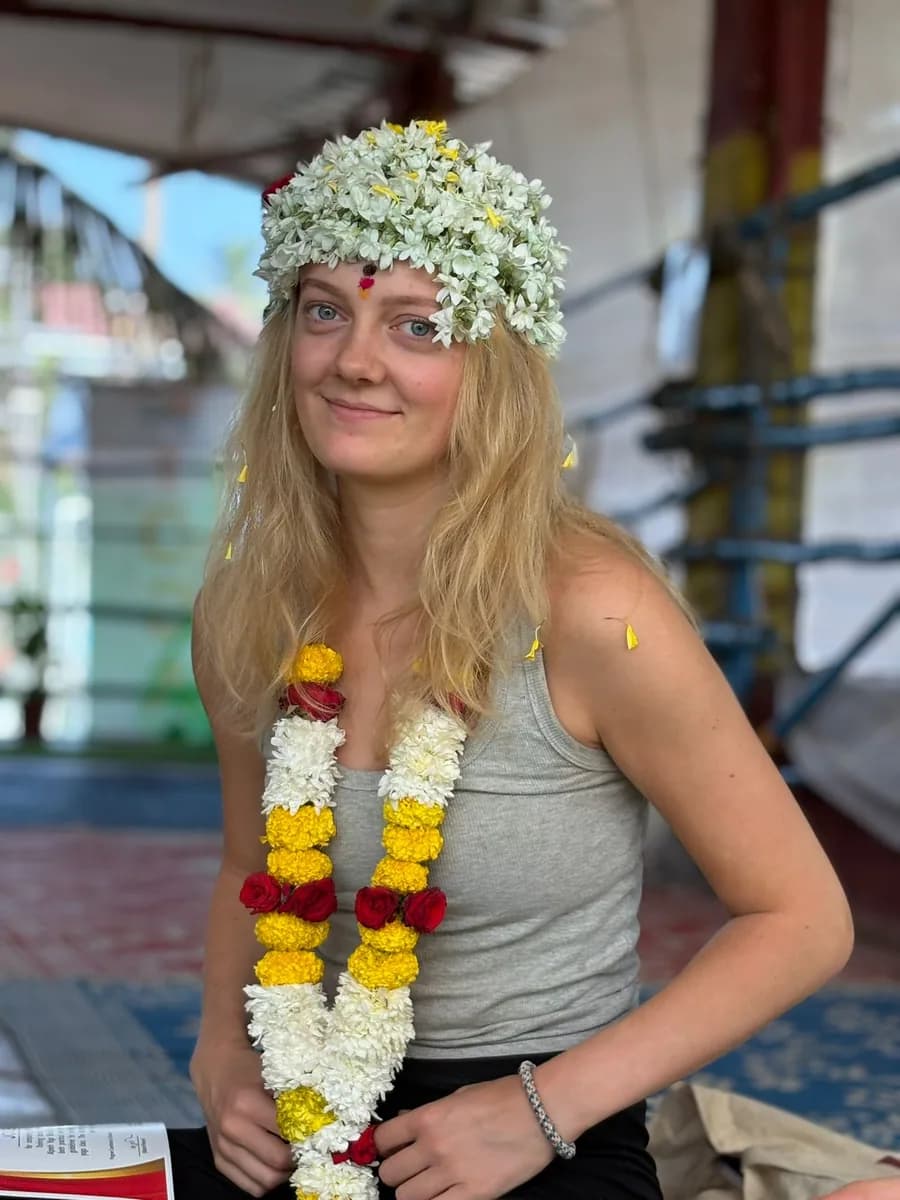 Yoga teacher training graduate wearing a jasmine flower crown and marigold garlands after her closing ceremony