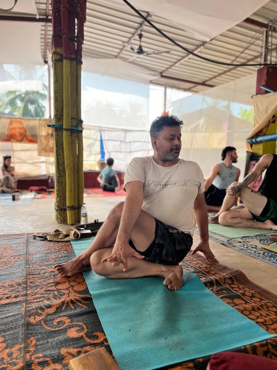 Alpesh Patwari demonstrating a bound seated pose while trainees follow along on their mats