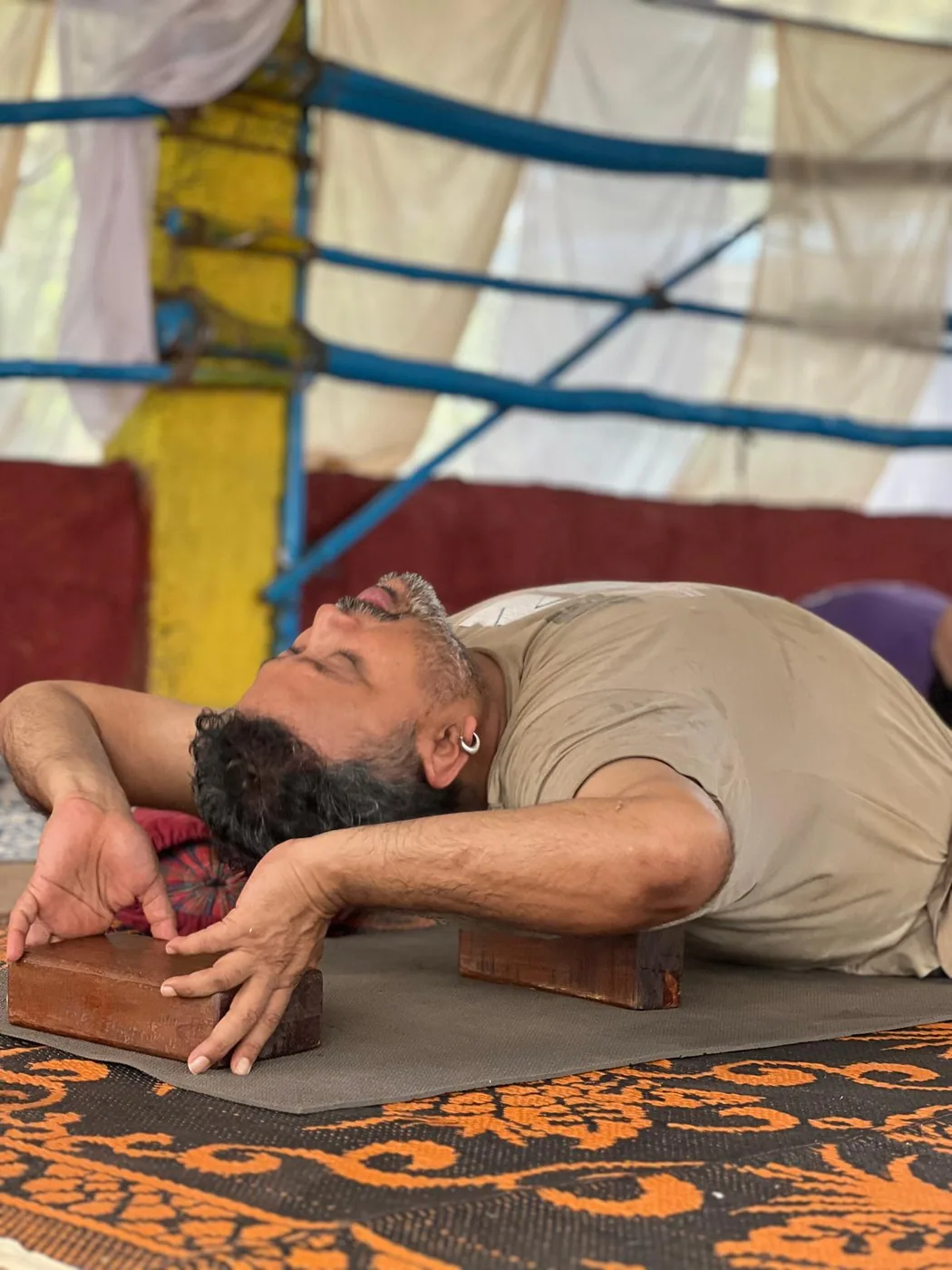 Reclined backbend supported on two wooden blocks, head resting back, during a props and alignment class at the shala